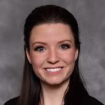 In this headshot, Michaela Althaus is wearing a black blazer and dark hair half pulled back.